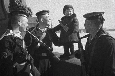 Моряки Балтийского флота с маленькой девочкой Люсей, родители которой умерли в блокаду. Фото Б.Кудояров. 1943 год.
